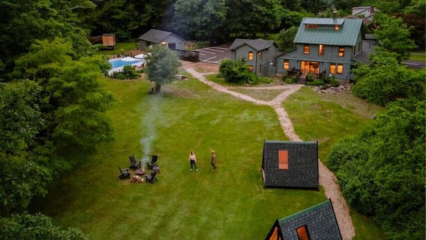 A large house with a green roof surrounded by lush greenery and a swimming pool.
