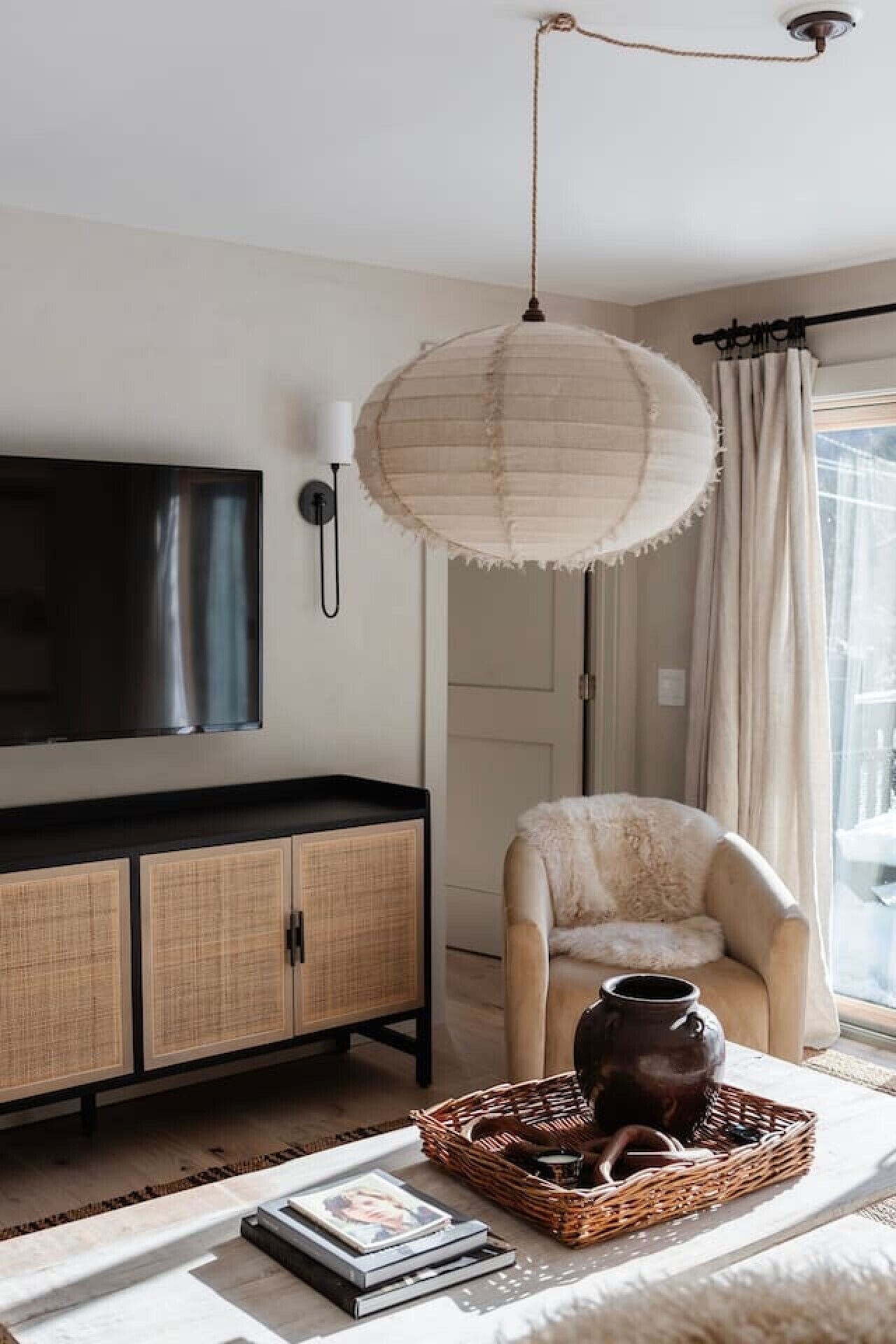 A living room with a flat-screen TV, a wicker basket with a vase, and a chair.