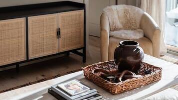 A living room with a flat-screen TV, a wicker basket with a vase, and a chair.