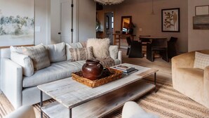 A living room with a sofa, coffee table, and a dining area with chairs and a table.