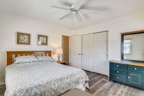 A bedroom with a bed, a nightstand, a lamp, a dresser, a mirror, and a door.