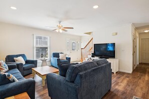 A living room with a TV, sofas, a coffee table, and a ceiling fan.
