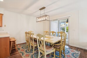 A dining area with a table and chairs, a hanging light fixture, and a patterned rug. - Captivating Canal Views at This Bayside Getaway in Bethany Beach! (Bethany Beach)