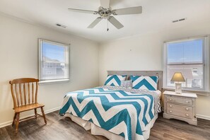 A bedroom with a bed, a wooden chair, a nightstand, a lamp, and a ceiling fan. - Captivating Canal Views at This Bayside Getaway in Bethany Beach! (Bethany Beach)