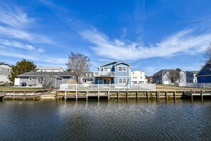 A waterfront property with a dock, a house with a blue exterior, and a white fence.