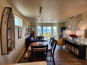 A spacious dining area with a wooden table and chairs, a bookshelf, and a staircase leading to another level. - Beachscape - Beautiful views (Ocean Shores)
