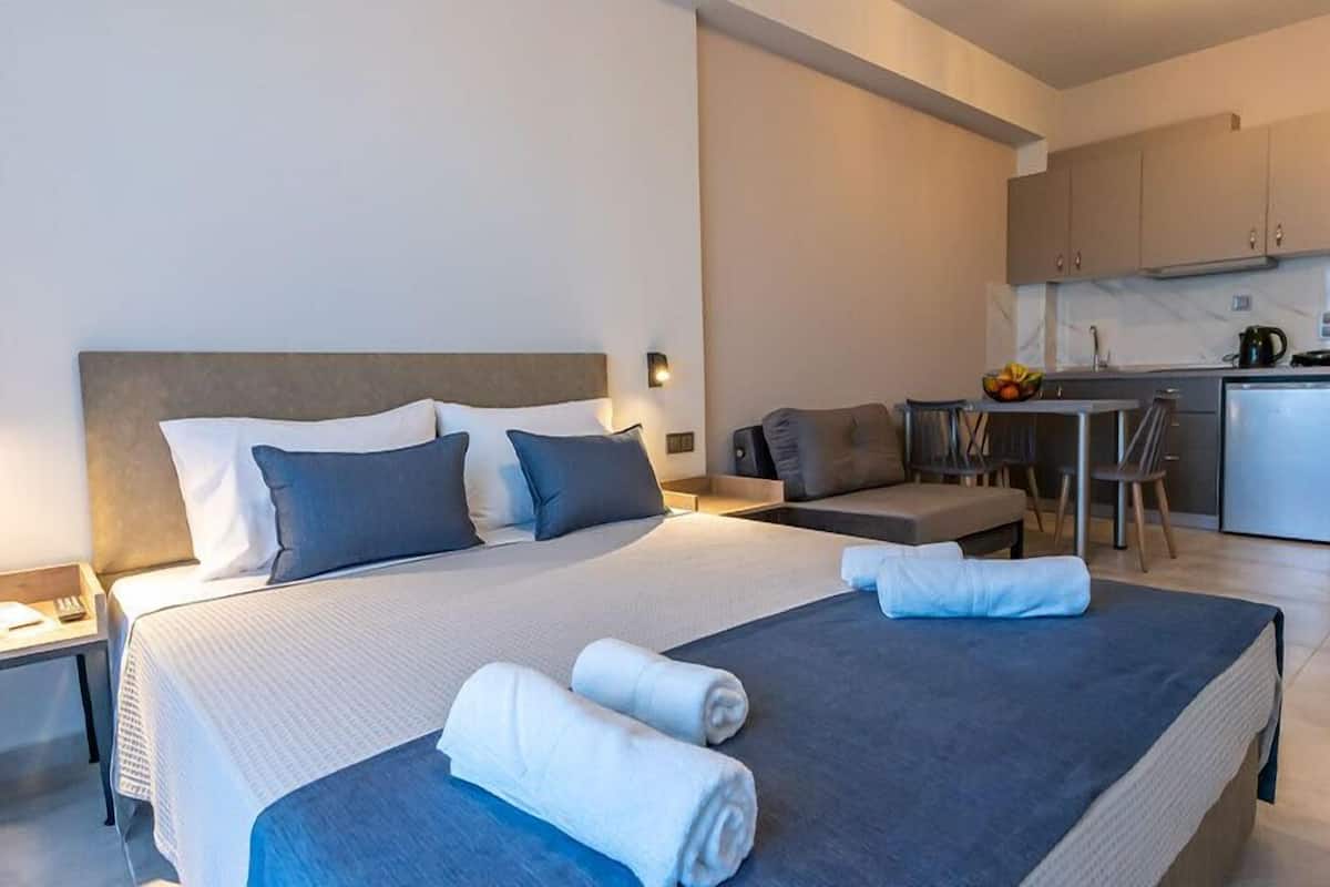 Ein modernes Hotelzimmer mit einem großen Bett, einem Schreibtisch und einer Küchenzeile.