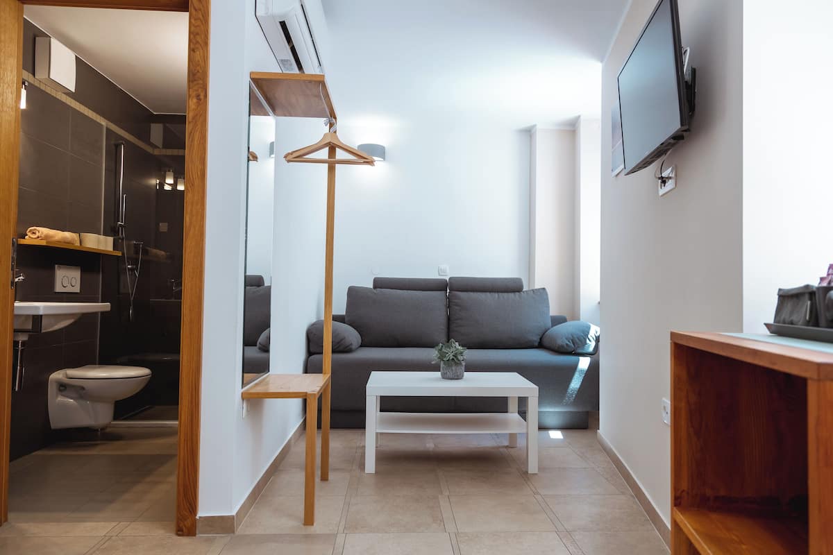 Un salon moderne avec un canapé gris, une table basse blanche et un téléviseur fixé au mur.