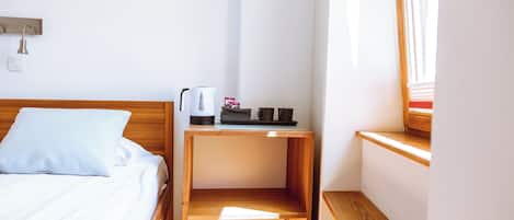 A neatly made bed with white linens and a wooden nightstand beside it.