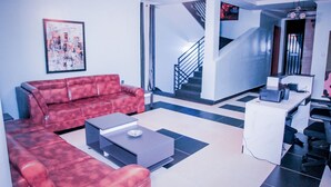 A modern living room with a red sofa, a coffee table, and a staircase leading to another area. - B&B MOUNTAIN VIEW (Kigali)