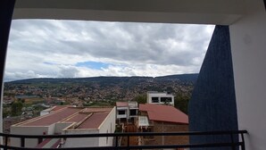 A balcony with a view of a densely populated town and distant hills under a cloudy sky. - B&B MOUNTAIN VIEW (Kigali)