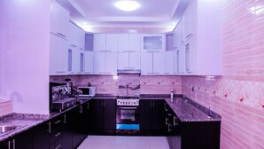 A compact kitchen with white cabinets, a built-in microwave, and a gas stove. - B&B MOUNTAIN VIEW (Kigali)