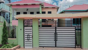 A two-story house with a gated entrance, a staircase to the upper floor, and a small garden area. - B&B MOUNTAIN VIEW (Kigali)