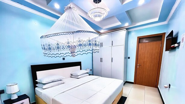 A bedroom with a bed, nightstands, a wardrobe, and a ceiling fan. - B&B MOUNTAIN VIEW (Kigali)