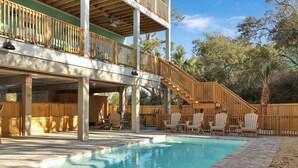 A pool area with wooden deck chairs, a wooden staircase, and a covered seating area. - Sacajawea by the Sea (Port St. Joe)