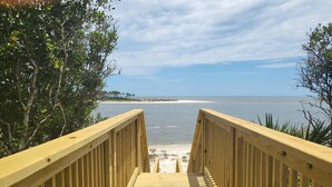 A wooden boardwalk leading to a beach with a clear view of the ocean and distant shoreline. - Sacajawea by the Sea (Port St. Joe)