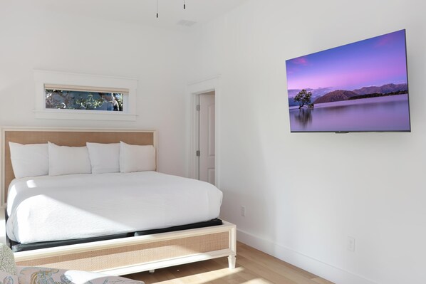 Relax in a serene bedroom with a large bed, flat-screen TV, and minimalist decor.