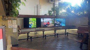 A seating area with a bench, a TV screen displaying nature scenes, and a no smoking sign.