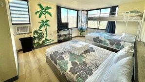 A hotel room with two beds, a TV, a window with curtains, and a plant.