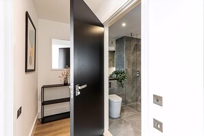 A modern bathroom with a glass shower enclosure, a toilet, and a vanity with a mirror.