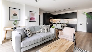 Una sala de estar moderna con un sofá gris, una mesa de centro de madera y una zona de comedor con una silla.