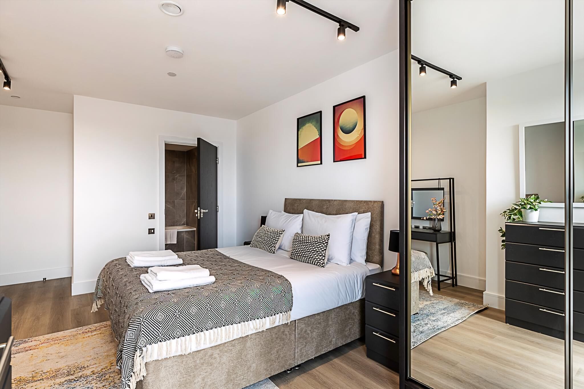 Un dormitorio moderno con una cama grande, un escritorio y un aparador.