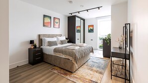 Un dormitorio moderno con una cama grande, mesitas de noche, un escritorio y obras de arte en las paredes.