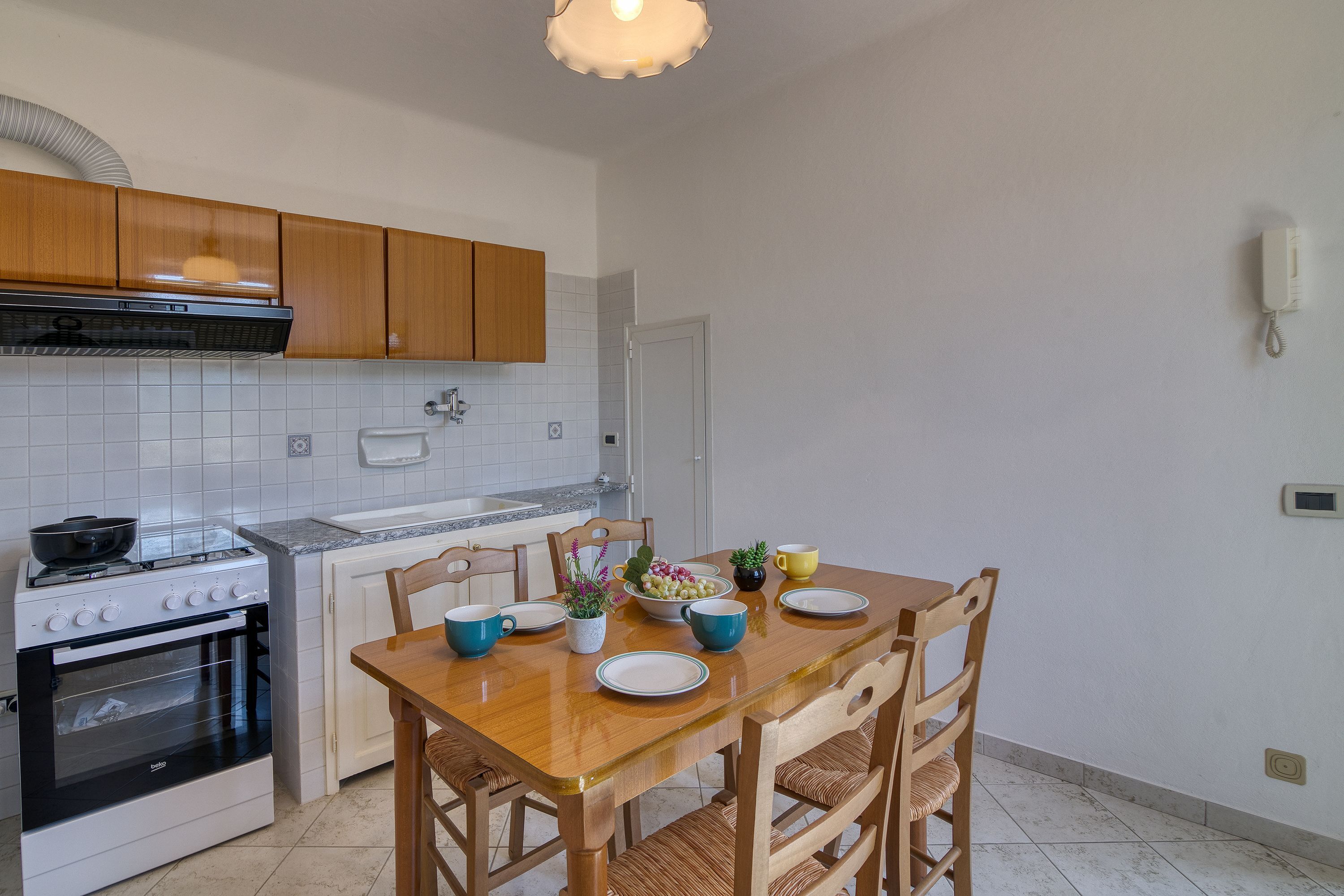 A kitchen with wooden cabinets, a white stove, and a dining table set with plates, bowls, and cups.