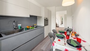 Eine moderne Küche mit Backofen, Spüle und einem Essbereich mit Tisch für zwei Personen.