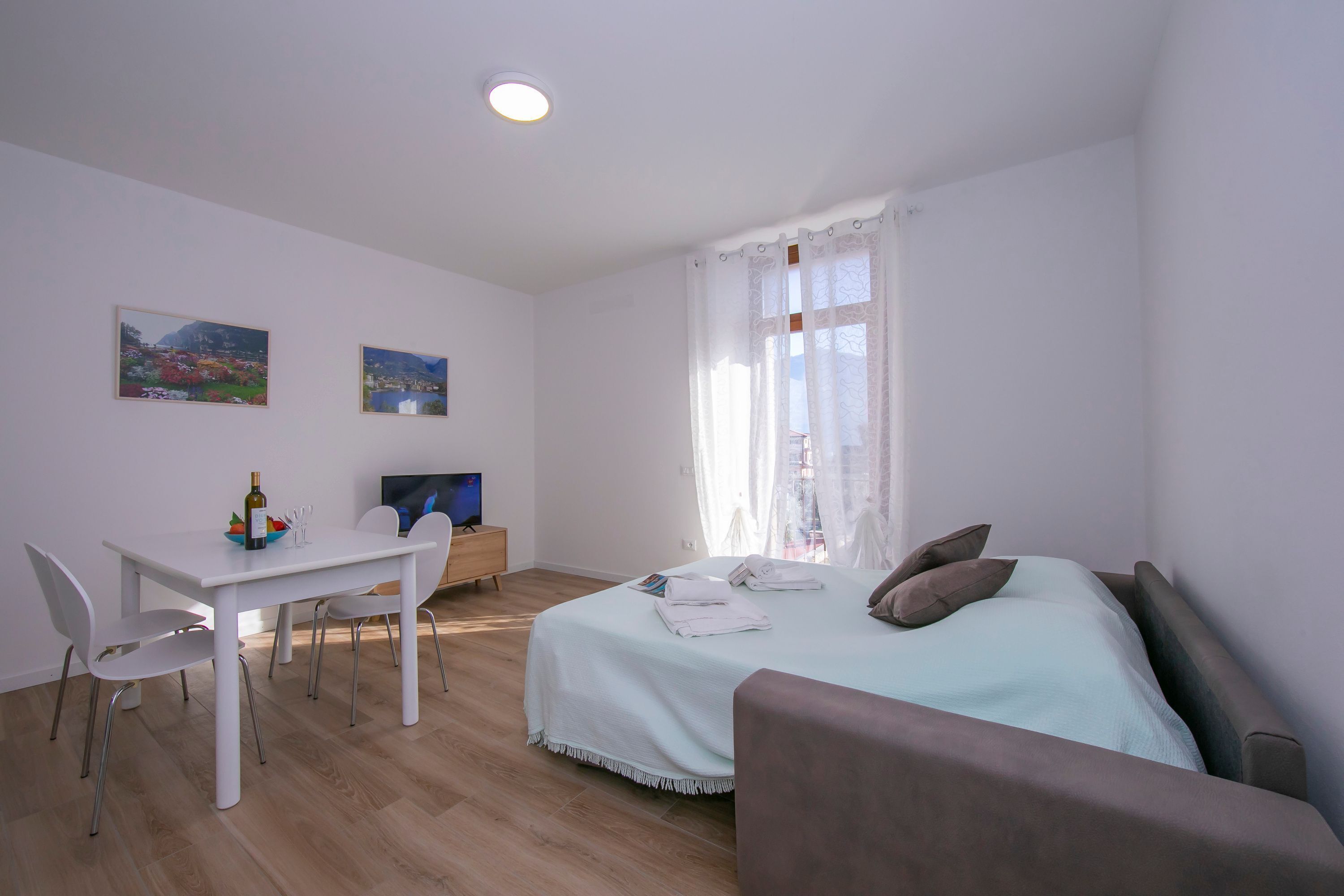 Ein Schlafzimmer mit Bett, Schreibtisch und Stuhl. An der Wand hängen zwei Gemälde.