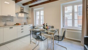 Une cuisine moderne avec une table à manger en verre, des appareils électroménagers en acier inoxydable et des poutres en bois.