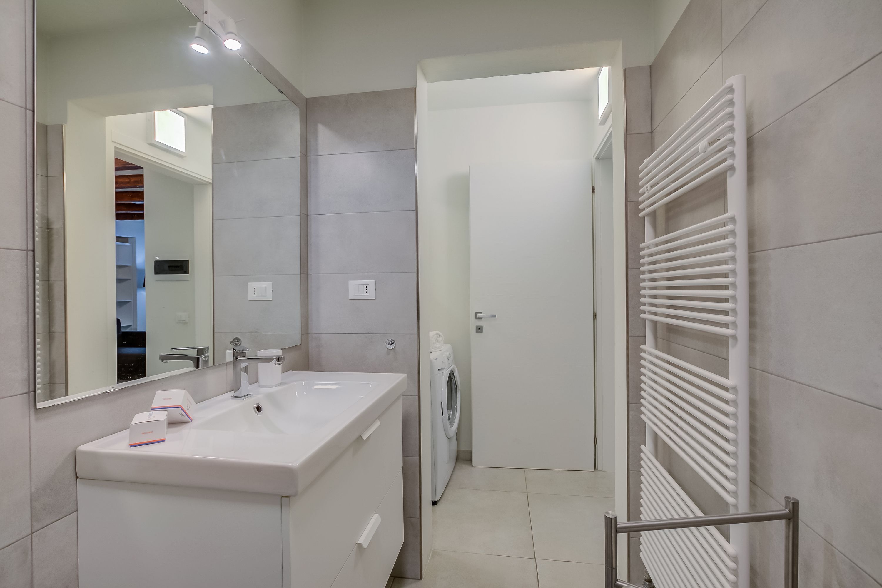 A modern bathroom with a white sink, mirror, and towel rack.