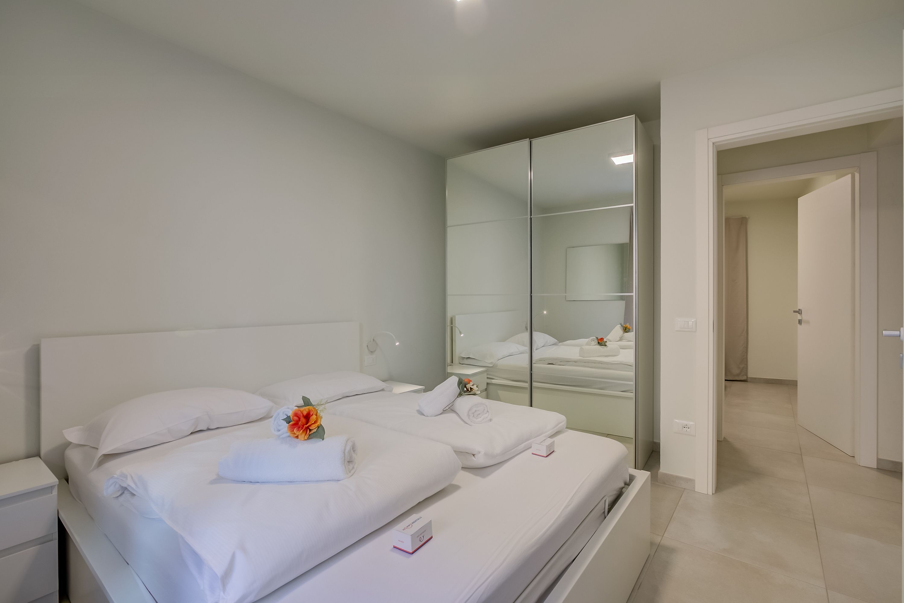 Une chambre d’hôtel moderne avec un grand lit, une table de chevet, un miroir et un dressing.