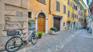 Une ruelle étroite pavée, bordée de bâtiments aux couleurs vives, un vélo garé sur le côté et un panneau indiquant un endroit situé à proximité.