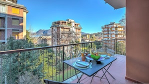 A balcony with a table set for dining, overlooking a mountainous landscape and neighboring buildings. - Alel Classy And Chic Apartment (Stresa)