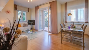 A modern living room with a glass coffee table, a sofa, and a dining area with a table and chairs. - Alel Classy And Chic Apartment (Stresa)