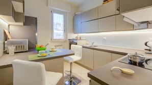 A modern kitchen with a dining area, featuring a refrigerator, oven, sink, and a bar stool. - Alel Classy And Chic Apartment (Stresa)