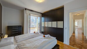 A modern hotel room with a large bed, a dark-colored wardrobe, and a view of the outdoors. - Antares in Riva del Garda (Riva del Garda)