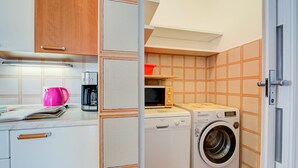 A compact kitchen with a washing machine, a microwave, and a coffee maker. - Antares in Riva del Garda (Riva del Garda)