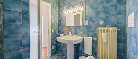 A bathroom with blue tiles, a white sink, a mirror, and a towel rack.