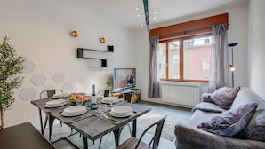 Un salon moderne comprenant un coin repas, un canapé, un téléviseur et une fenêtre avec des rideaux.
