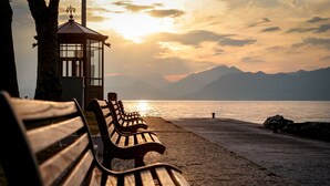 A wooden bench and a glass gazebo by a lakeside during sunset. - Borgo Degli Ulivi in Toscolano Maderno (Toscolano Maderno)