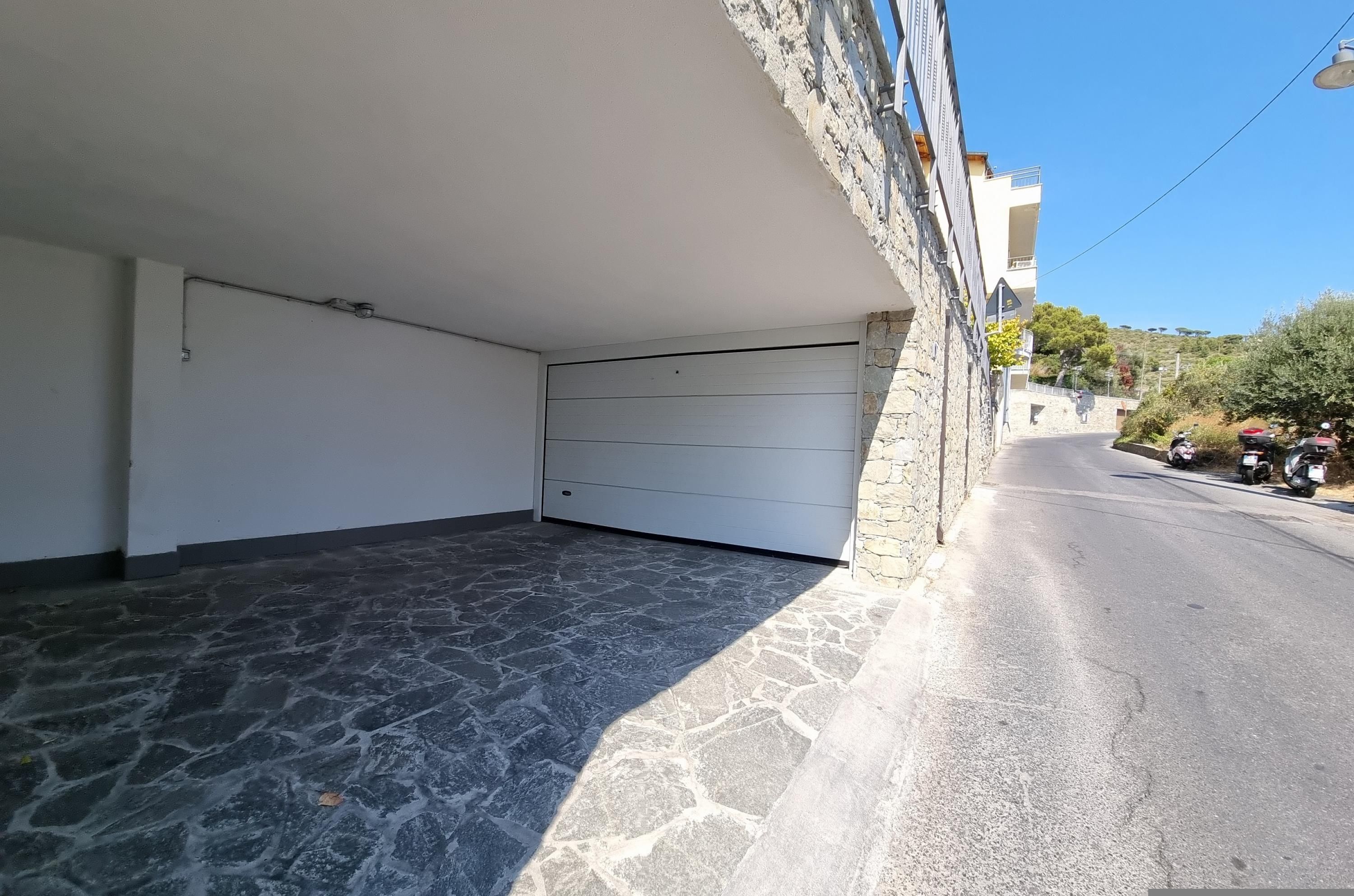 A spacious, stone-floored room with a white ceiling and a garage door.