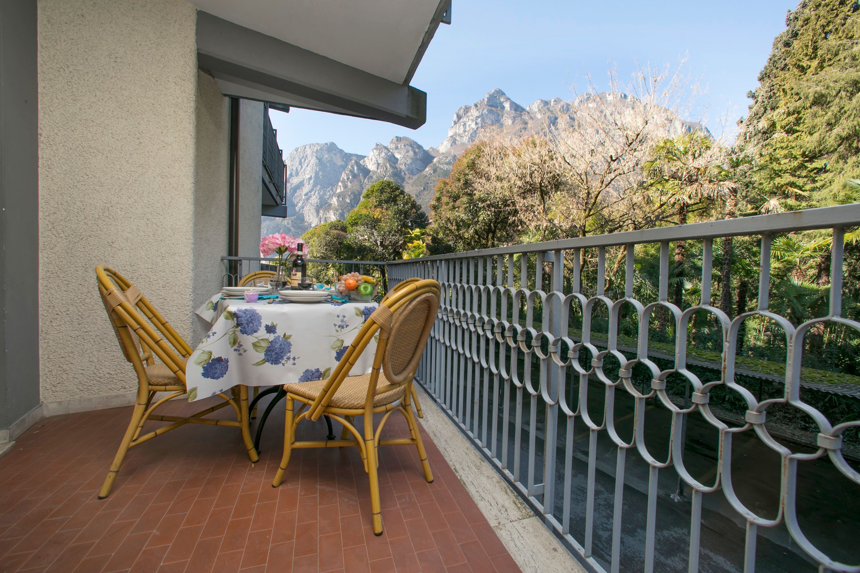 A balcony with a table set for two, overlooking a mountainous landscape.