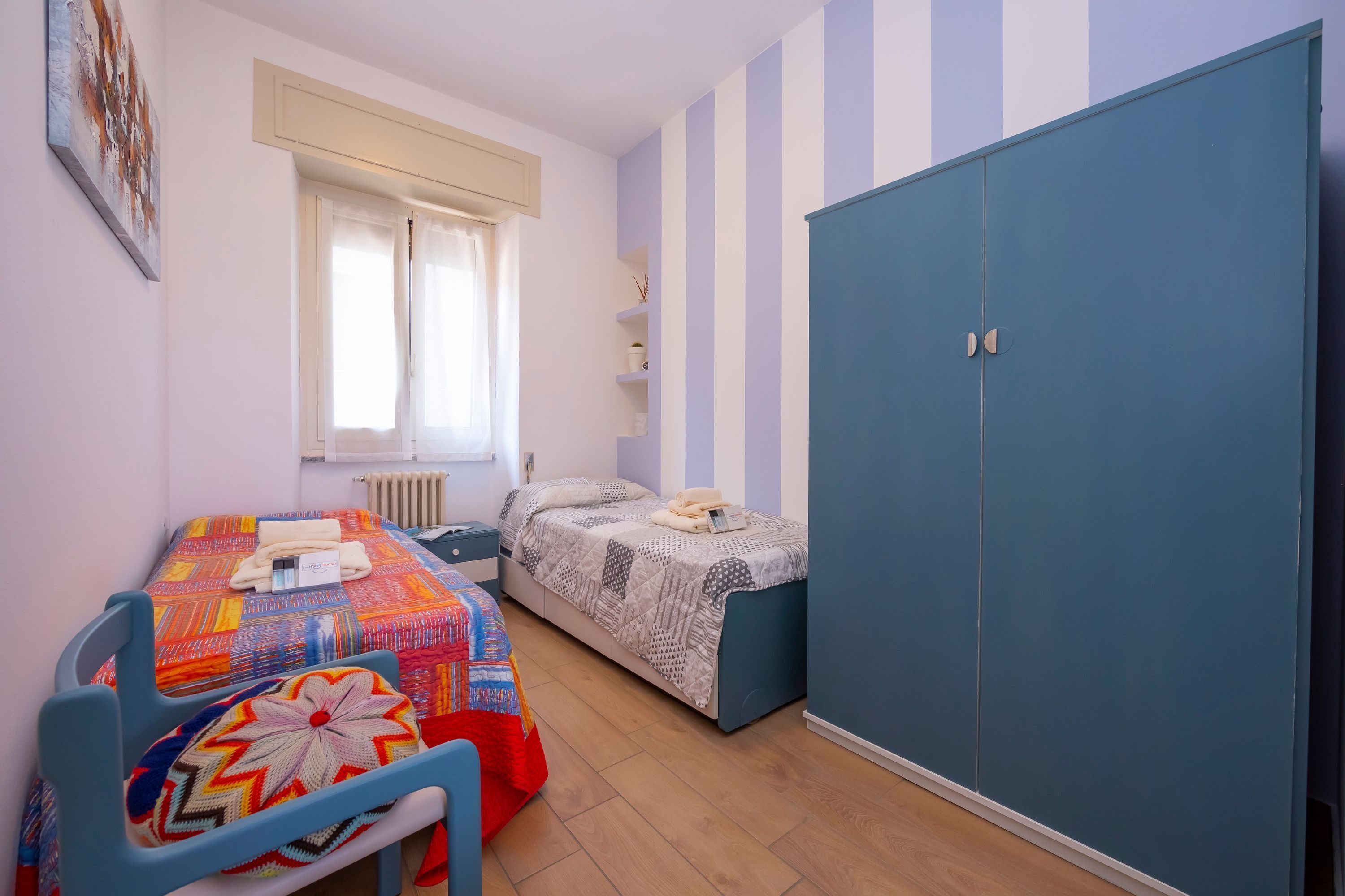 Ein Schlafzimmer mit zwei Betten, einem Kleiderschrank und einem Fenster mit Vorhängen.