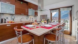 Una cocina con una isla central, taburetes de bar y vistas a las montañas a través del ventanal.