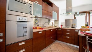 Una cocina moderna con electrodomésticos de acero inoxidable, armarios de madera y salpicadero de azulejos.
