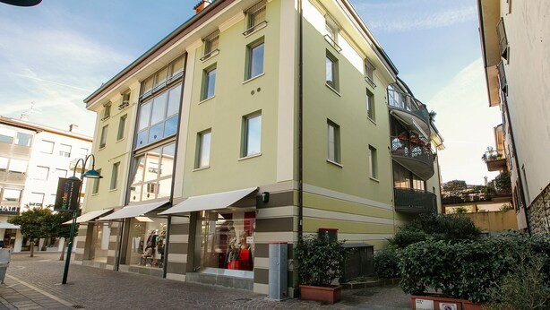 A multi-story building with a ground-floor shop and a visible balcony. - Riva Centro Apartment (Riva del Garda)