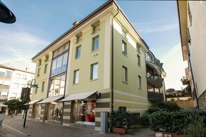 Un immeuble à plusieurs étages, avec un commerce au rez-de-chaussée et un balcon bien visible.