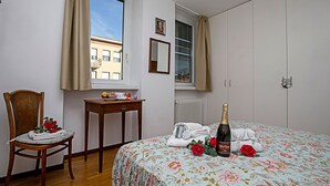 A bedroom with a bed, a chair, a table, and a window. - Riva Centro Apartment (Riva del Garda)